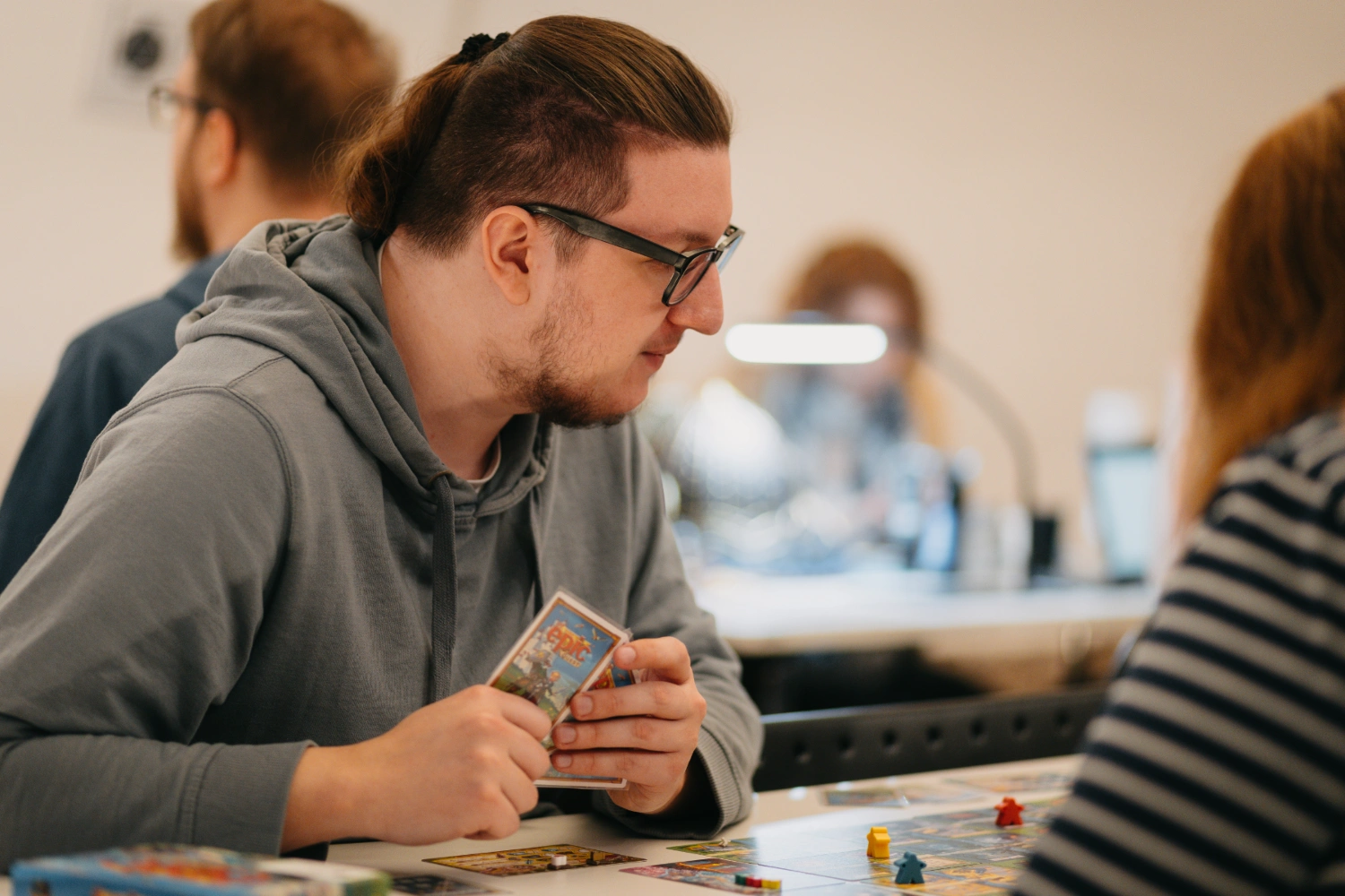 Konzentrierter junger Mann hält Karten während einer Strategiespielrunde.