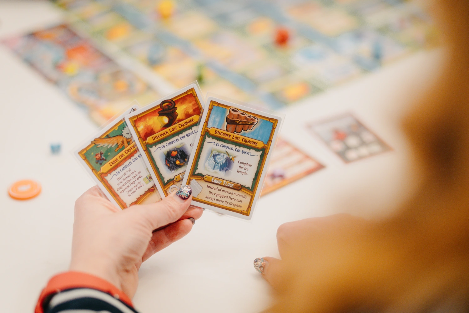 Nahaufnahme von Spielkarten vor einem Spielfeld.