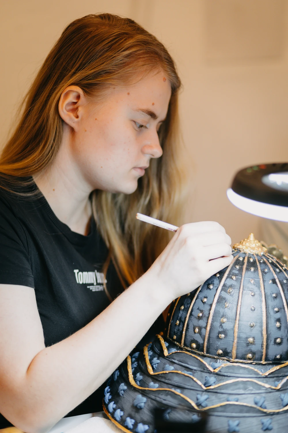 Frau bemalt sorgfältig einen Helm mit vielen Details für ein Cosplay.