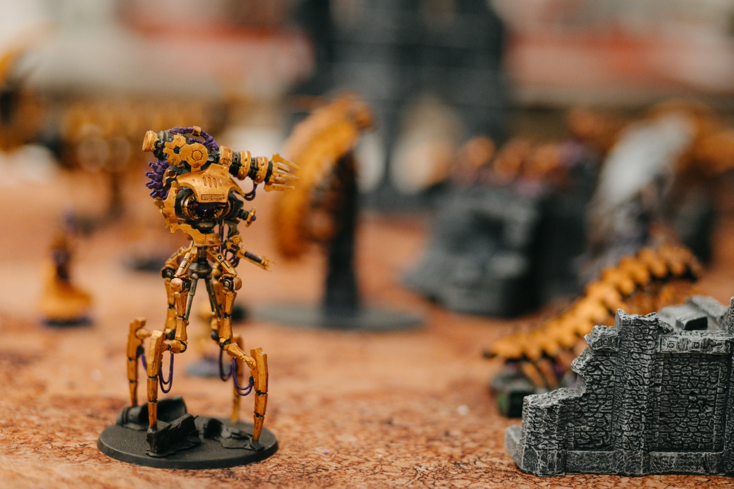Nahaufnahme einiger gold bemalter Warhammer Miniaturen am Spielfeld.