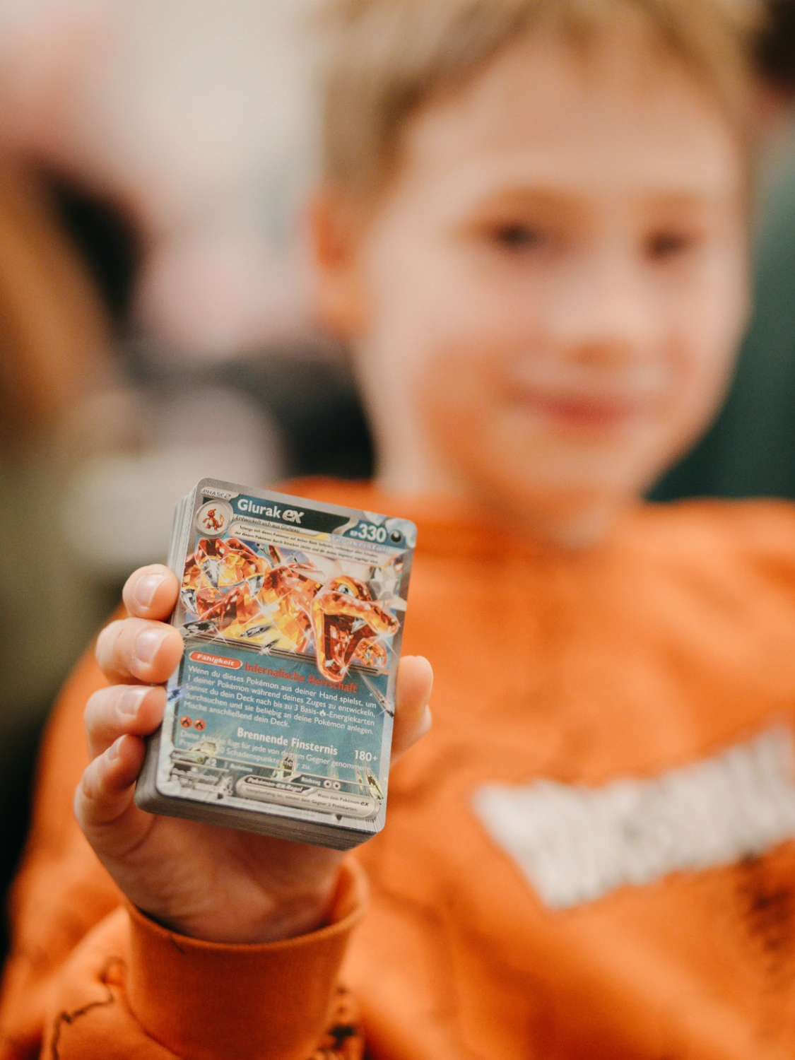 Kind hält Pokémon Karte in die Kamera.