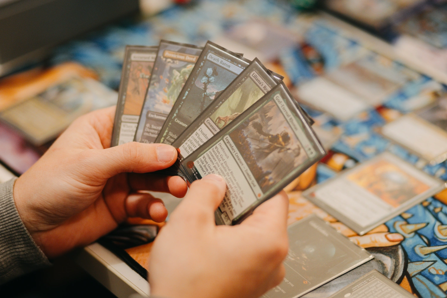 Person hält Spielkarten eines Sammelkartenspiels in der Hand.
